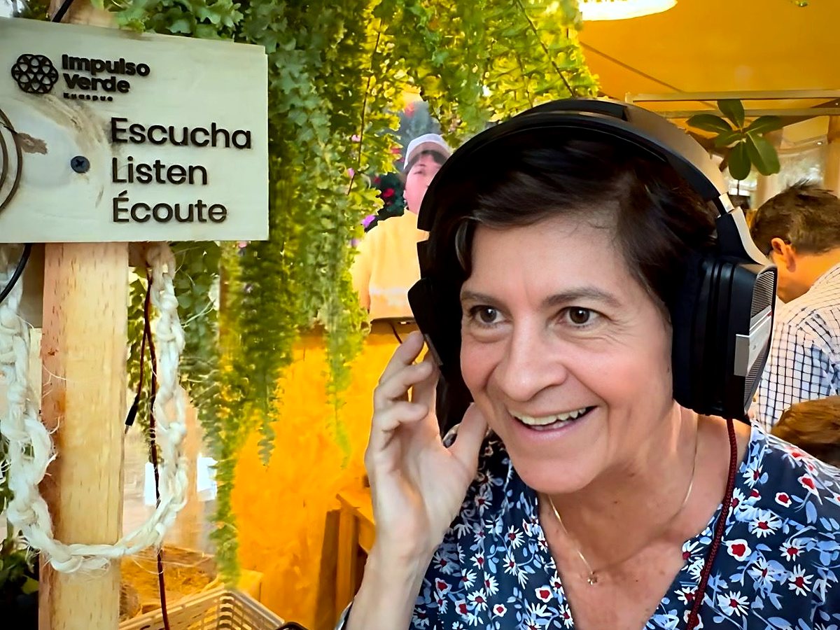 Asistente sonriendo con audífonos mientras escucha la música de las plantas