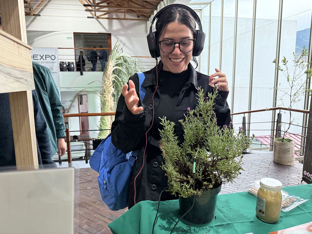 Participante con audífonos sonríe mientras escucha una planta de romero